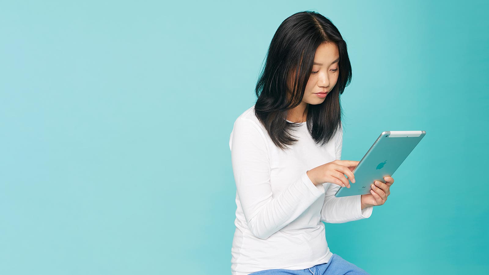 Woman sitting using iPad.