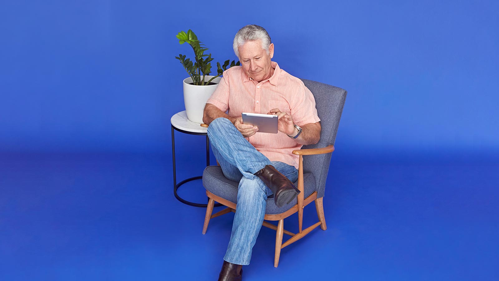 Man reclined in chair, using iPad.