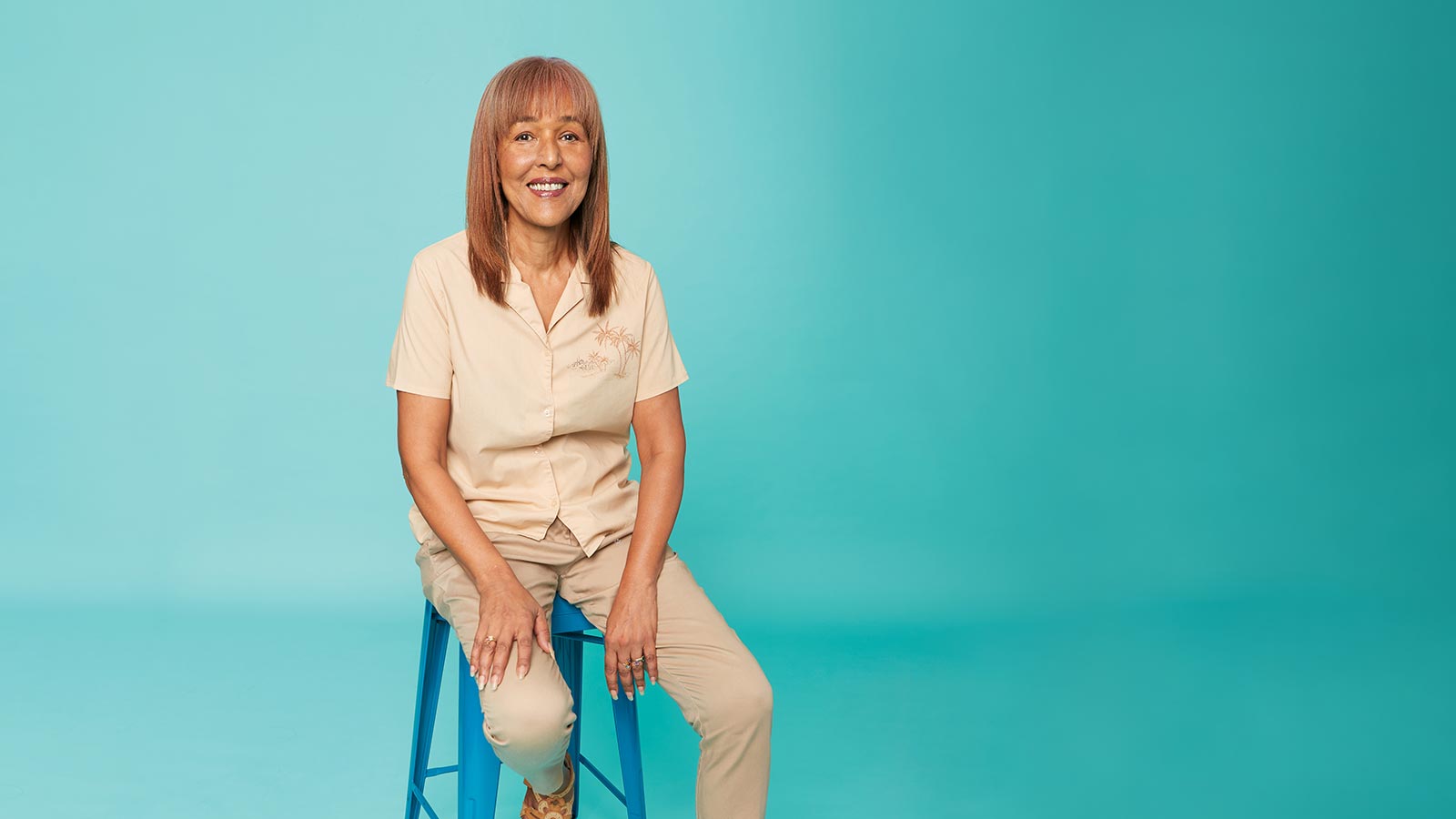 Woman sitting on a stool, smiling.
