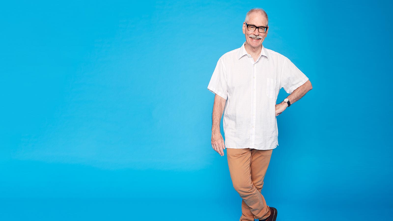 Man standing with hand on hip looking happy.