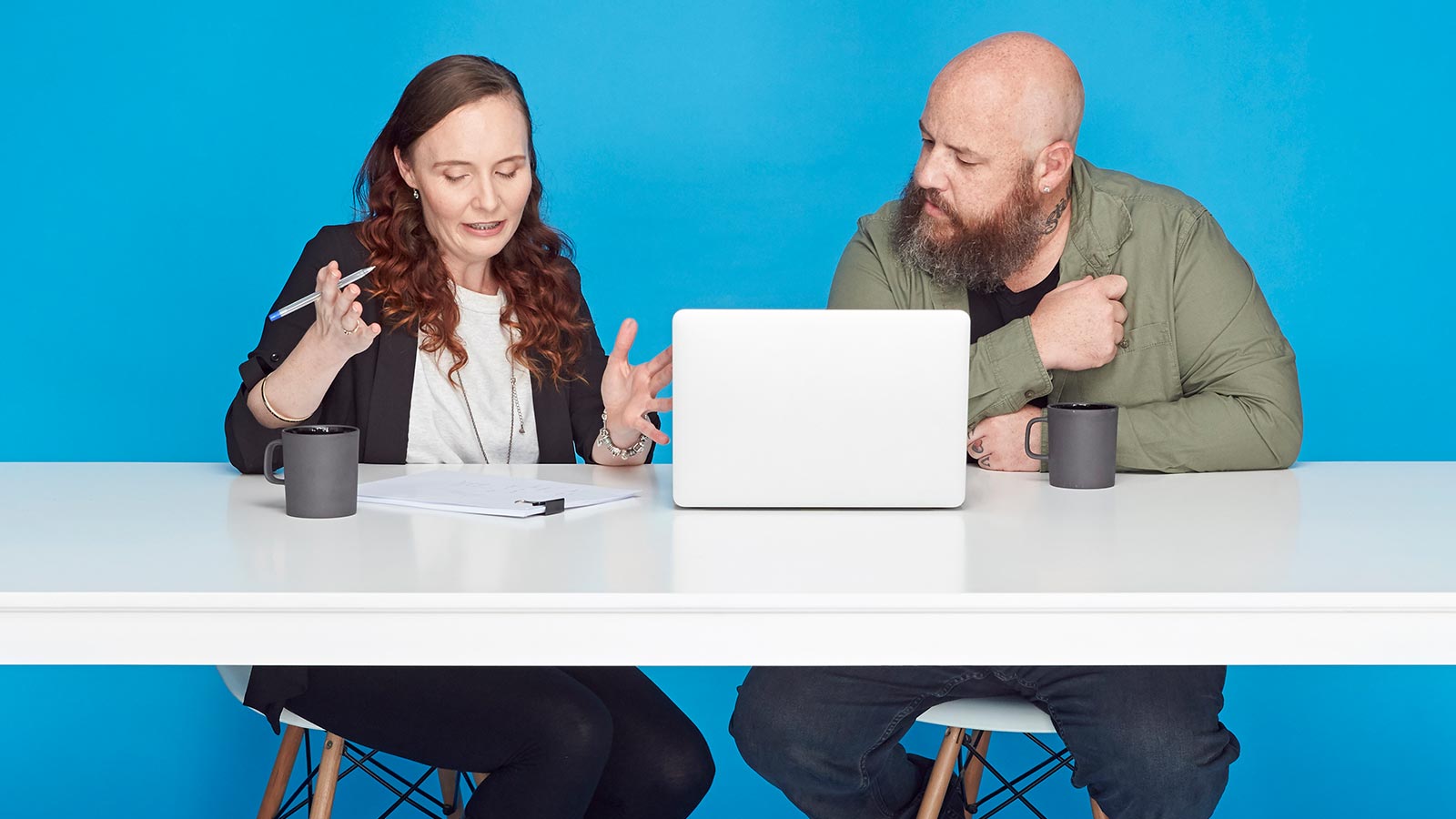 Couple sitting in front of a laptop, drinking coffee.