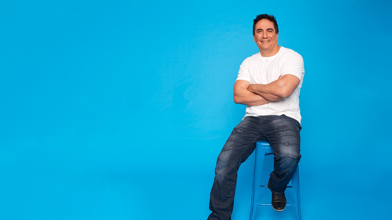 Man relaxing on stool looking happy.